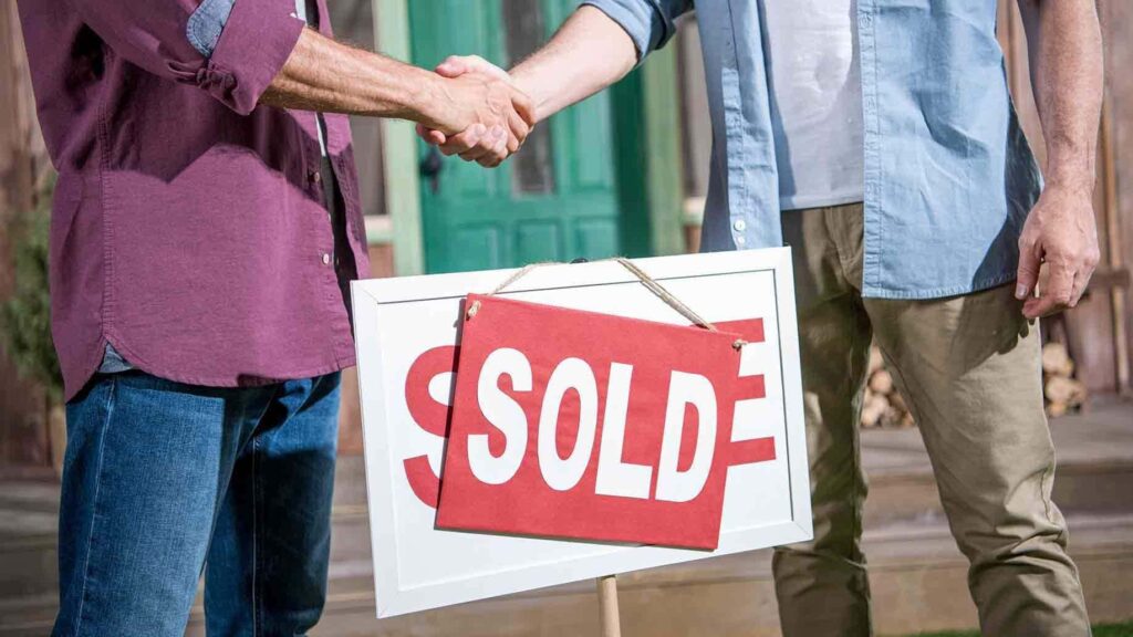 two people shaking hands after sale of house